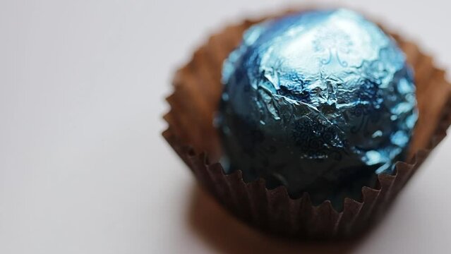 round chocolate candy in colored foil rotates in a circle