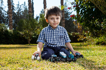 Boy is playing a cars multitrack on the garden 