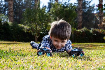 Boy is playing a cars multitrack on the garden 