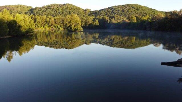 Survol d'un lac &agrave; l'aube avec une multitudes de reflets. Etang au lever de soleil film&eacute; de pr&egrave;s.