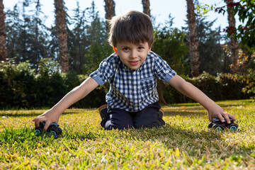 Boy is playing a cars multitrack on the garden 