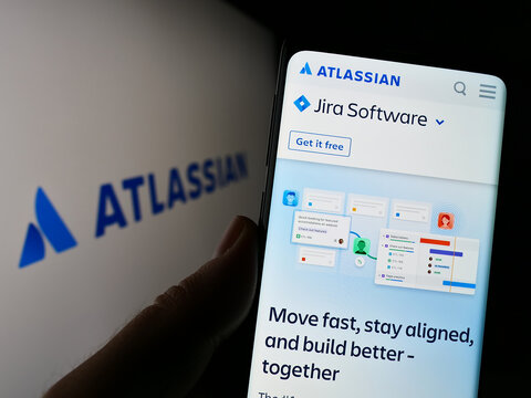 Stuttgart, Germany - 12-30-2022: Person holding smartphone with webpage of Australian software company Atlassian Corporation on screen with logo. Focus on center of phone display.