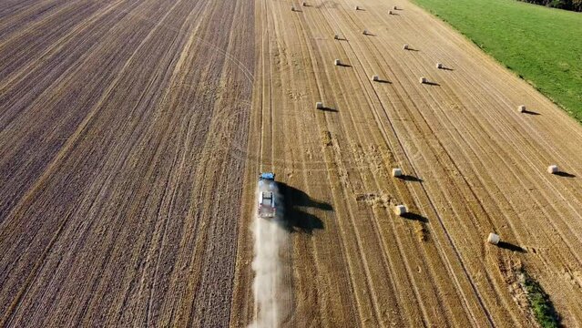 Tracteur roulant rapidement sur un champ avec une grosse tra&icirc;n&eacute;e de poussi&egrave;re.
