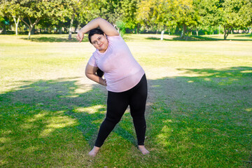 Beautiful Overweight indian woman exercising outdoors in park. Asian fat female workout in nature,...