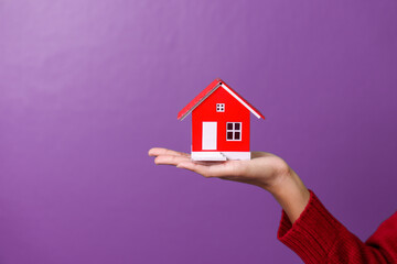 Close up asia cheerful girl holding home toy model showing copy space ad isolated over violet color background, for valentine day color tone