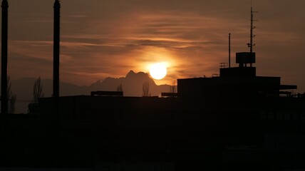 Fototapeta na wymiar Sunset over industrial building and mountains