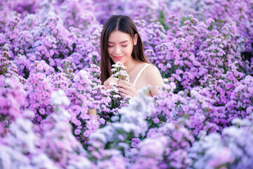 asian woman wearing white dress happily and smelling flowers in the flowers garden. travel relax on vacation concept..
