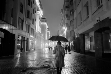 man walking at night in the city with an umbrella