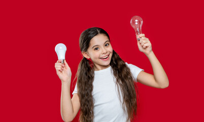 surprised girl with energy saving bulb isolated on red. girl with energy saving bulb in studio.