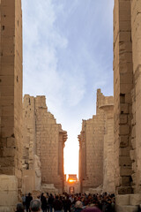Vertical view of tourist people walking along the Egiptian Karnak temple ruins located in Luxor at sunrise