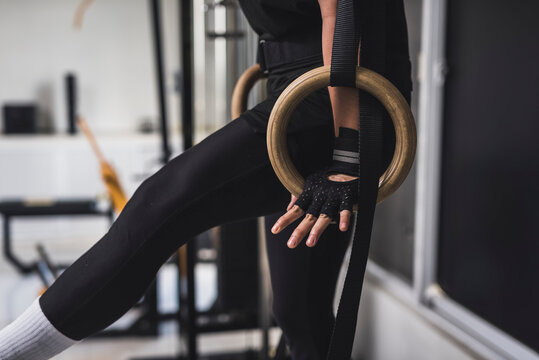 An anonymous man doing an L-sit exercise on wooden still rings at the gym. Calisthenics exercises on gymnastics rings.