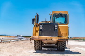 Yellow tractor, construction equipment, road repair.