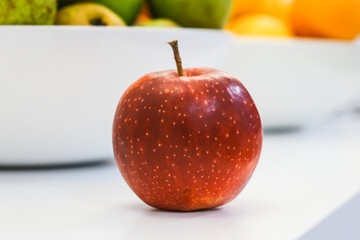 Red fresh apple in a bright kitchen. Side view, close-up.