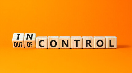 In or out of control symbol. Concept words In control and Out of control on wooden cubes. Beautiful orange table orange background. Business in or out of control concept. Copy space.