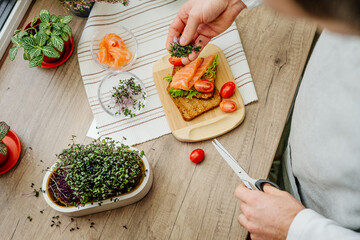 Closeup of man cutting microgreens of radish making sandwich