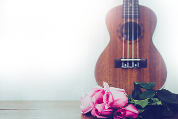 close up of pink roses laying and ukulele on top of wooden table with window light, love concept , Valentines , music poster white background with copy space