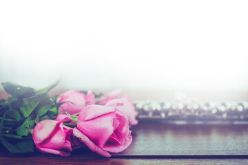close up of pink roses and blurred flute on wooden table against window light , love concept , Valentines background with copy space