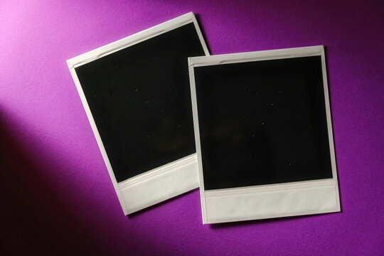 Two blank cards on purple background. Blank square photo frame on wall copy space