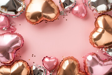 Saint Valentine's Day concept. Top view photo of heart shaped pink silver golden balloons and confetti on isolated light pink background with empty space in the middle
