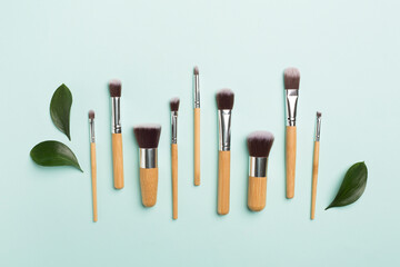 Natural biodegradable makeup brushes on color background, top view