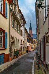 Nice view of a narrow alley leading to the famous church Heiliggeistkirche located in the marketplace in the old town centre of Heidelberg, Germany, on a cloudy day in winter.