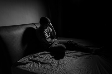 Man with depression sitting in a dark room.  Depression is a low mood that lasts for a long time,...