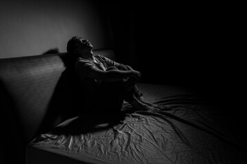 Man with depression sitting in a dark room.  Depression is a low mood that lasts for a long time,...