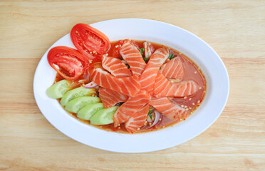 Salmon spicy salad in dish on wood table background. Top view.