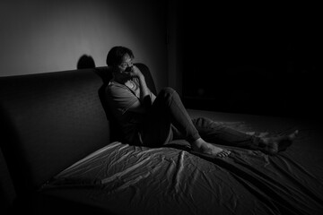 Man with depression sitting in a dark room.  Depression is a low mood that lasts for a long time,...
