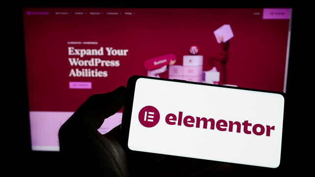 Stuttgart, Germany - 12-30-2022: Person holding mobile phone with logo of Israeli software company Elementor Ltd. on screen in front of business web page. Focus on phone display.