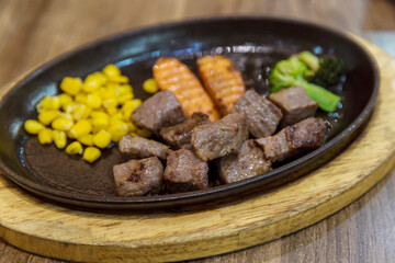 Saikoro Steak and Stir-fried Mixed Vegetable with Soy Sauce. Garlic Saikoro Steak. medium rare dice wagyu topping with mince carrot on hot plate served