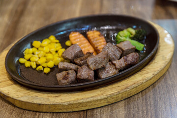 Saikoro Steak and Stir-fried Mixed Vegetable with Soy Sauce. Garlic Saikoro Steak. medium rare dice wagyu topping with mince carrot on hot plate served