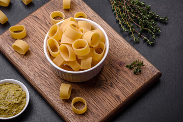 Raw uncooked pasta in a white ceramic bowl with spices and herbs