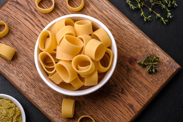 Raw uncooked pasta in a white ceramic bowl with spices and herbs