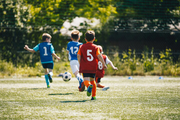 Group of School Children Play Sports Game. Happy Kids Running and Kicking Soccer Ball. Boys in Red...
