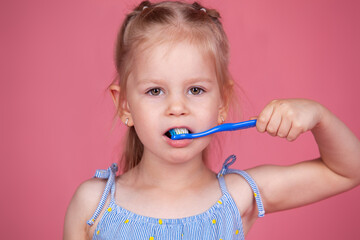 little girl brushes her teeth with a blue brush