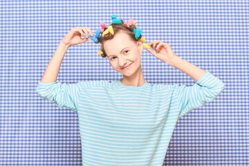 Portrait of happy young woman with colorful hair curlers on head