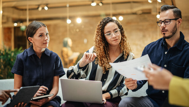 Multiethnic Group of People Meeting and Discussing Innovative Ideas in a Casual Conference Room in the Office. Smiling Colleagues Putting Together a Presentation