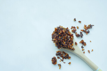 chili and garlic flakes on a wooden spoon on white background 