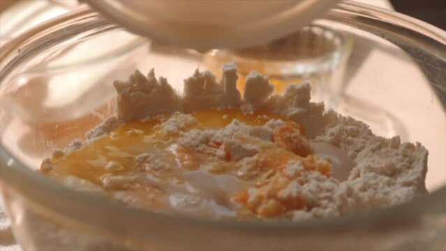 Pouring yeast dissolved in milk  into flour and egg in the bowl