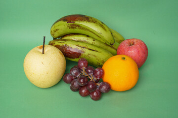 Pear, grape, banana, orange and apple fruits isolated on green background