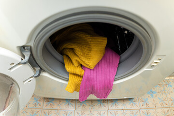 colored clothes sticking out of the washing machine.
