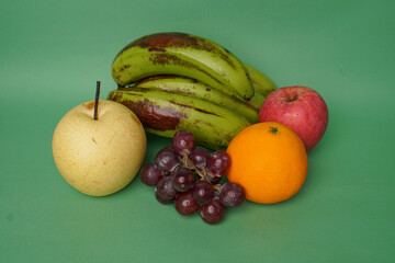 Pear, grape, banana, orange and apple fruits isolated on green background
