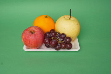 Pear, grape, banana, orange and apple fruits isolated on green background