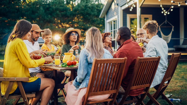 Group of Multiethnic Diverse People Having Fun, Communicating with Each Other and Eating Vegetarian Meals at an Outdoors Dinner. Relatives and Friends Gathered Outside Their Home on Warm Summer Day.
