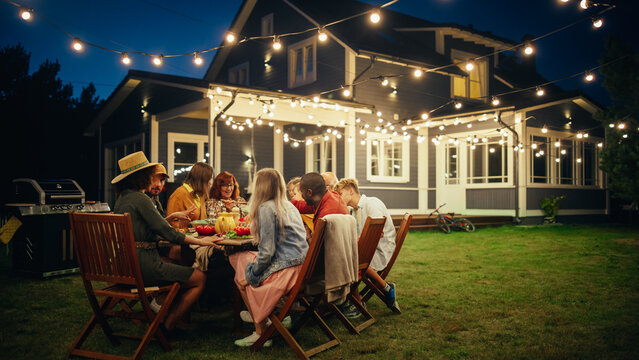 Group of Multiethnic Diverse People Having Fun, Sharing Stories with Each Other and Eating at Outdoors Dinner Party. Family Gathered Outside Their Home on a Warm Summer Evening.
