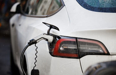Electric Vehicle charging station system storing power on a white modern car. EV fuel for advanced hybrid car