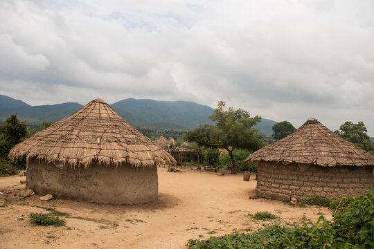 African village in Nigeria near capitol city of Abuja. Traditional African houses made of mud walls and wattle roofs, with untouched nature with hills and mountains in background