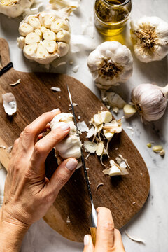 Fresh white garlic bulb and cloves. Hands preparing garlic.