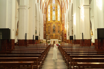 Asian Vietnamese woman praying in empty christian church with cross, architecture design. Religious beliefs. Catholic religion. Jesus worship. People lifestyle.